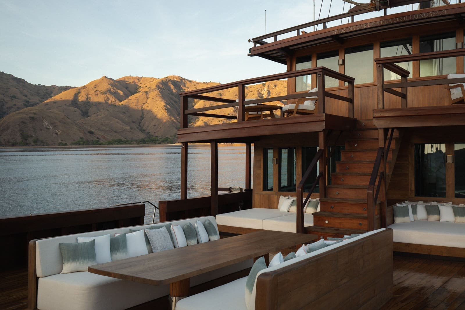 2 story wooden boat with couches, chares and dry mountains of Comodo in the background.